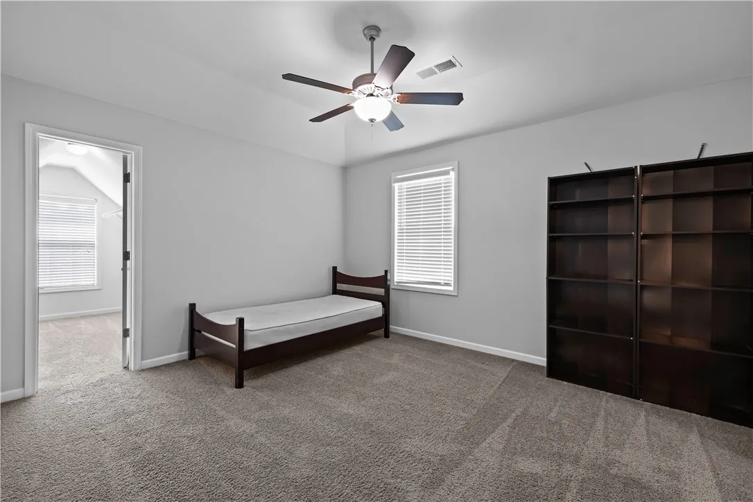 A comfortable bedroom with soft carpeting and a ceiling fan for year-round comfort.