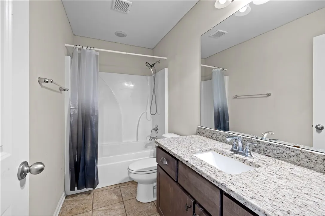 A pristine bathroom featuring a vanity with granite counters and a clean shower/tub combination.