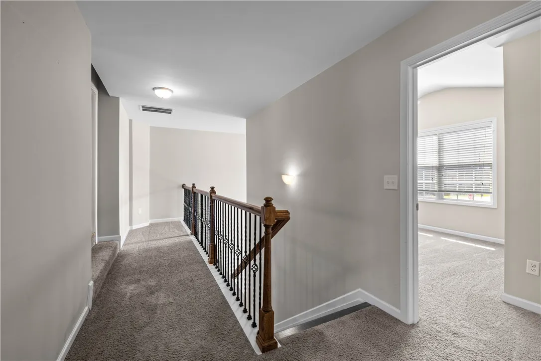 Upper-level landing connecting private spaces with comfortable, neutral carpeting and classic balustrade.