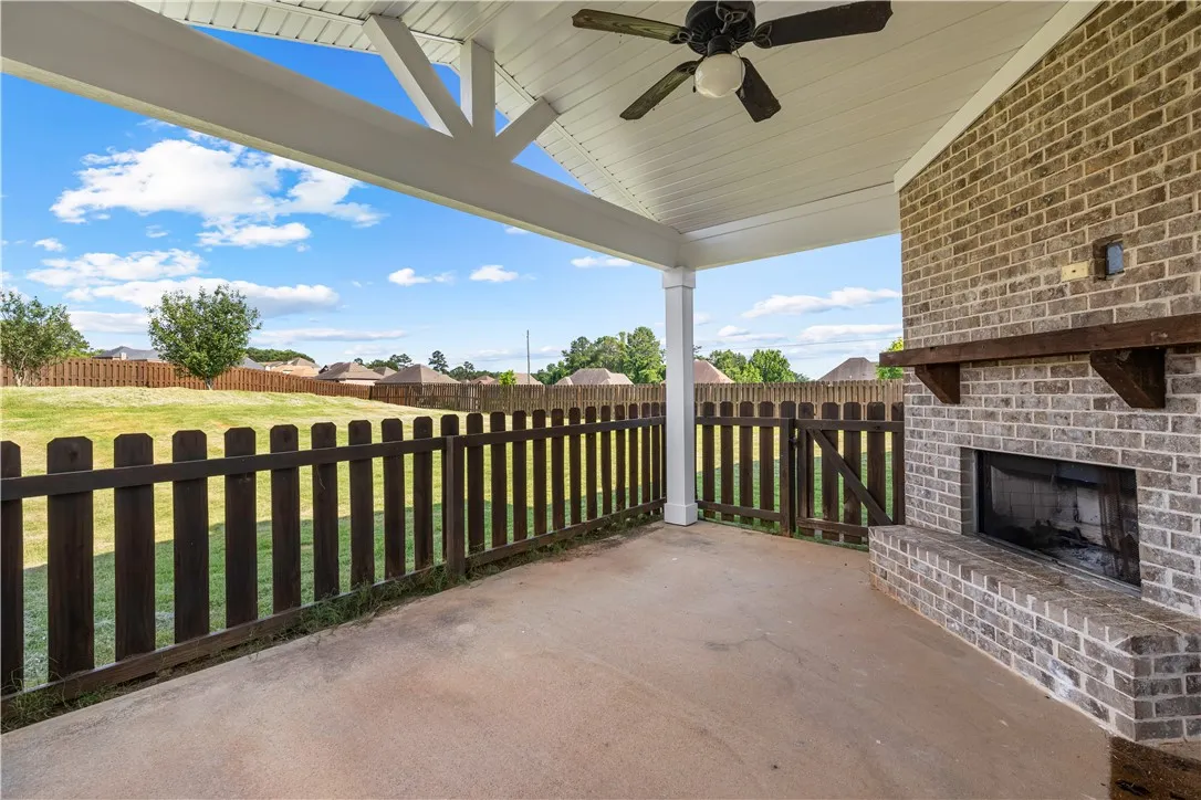 A spacious covered patio features a brick fireplace, offering a perfect outdoor living space.