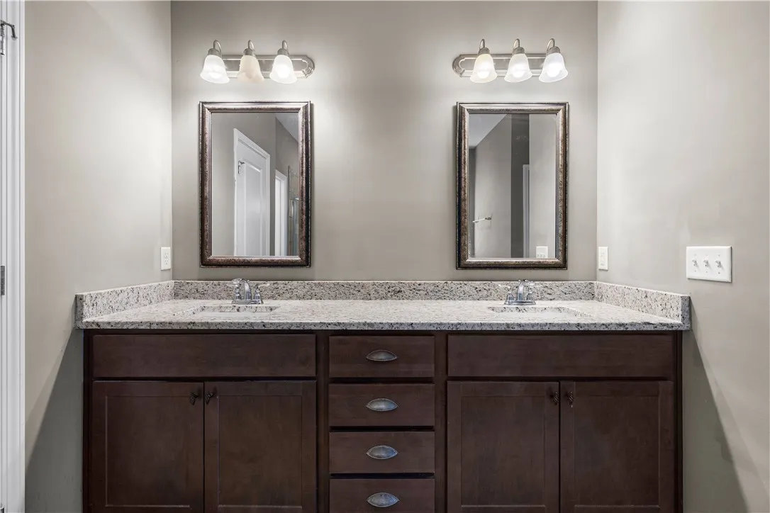 Twin vanities with granite counters and rich cabinetry create a balanced and functional primary bath.