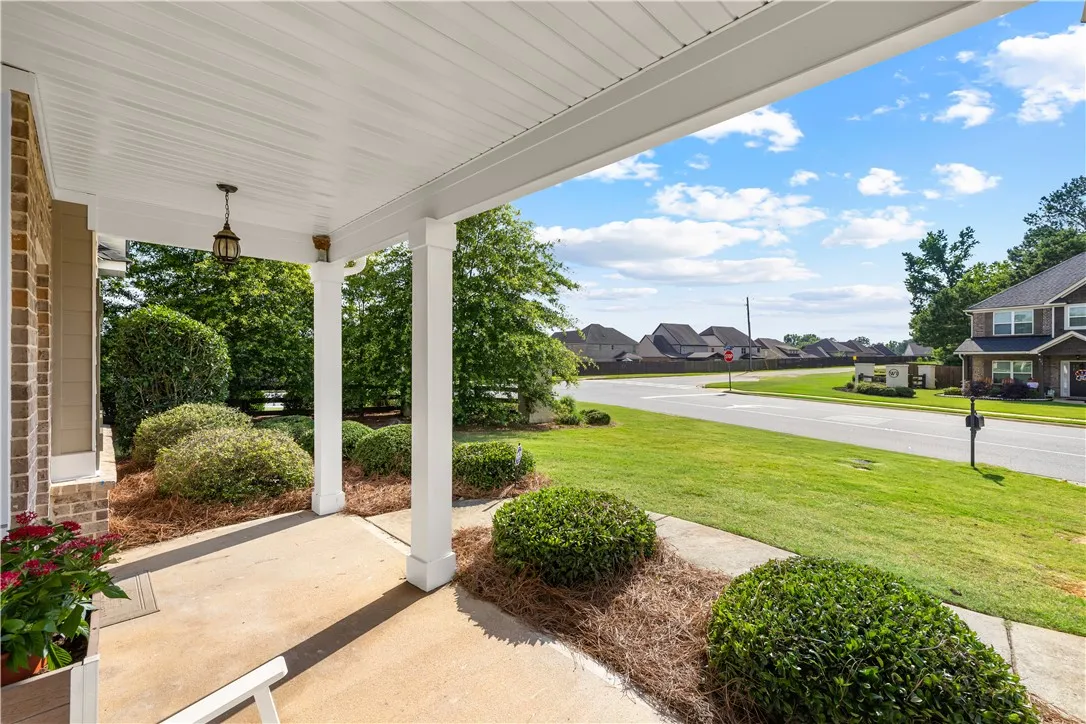 A welcoming front porch, adorned with manicured shrubs, offers a pleasant neighborhood street view.