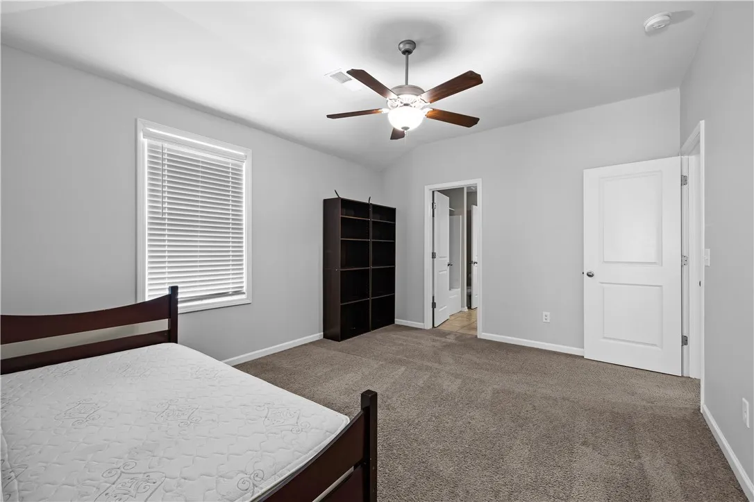 A comfortable bedroom with soft carpeting and a classic ceiling fan, perfect for restful nights.