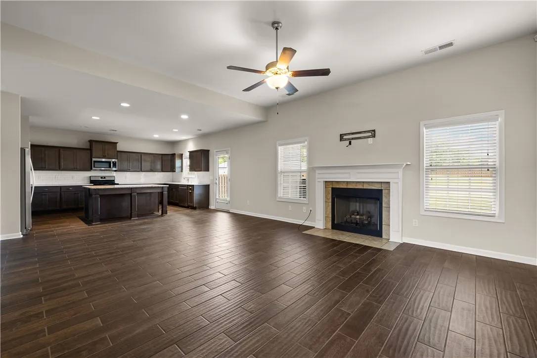 An open-concept living area presents a kitchen island and a cozy fireplace with tile surround.