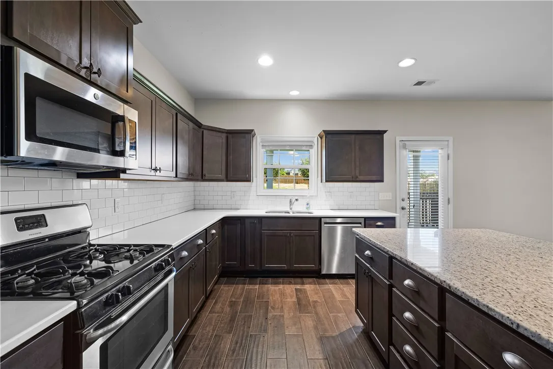 Culinary delights await in this modern kitchen with granite countertops and rich wood cabinetry.