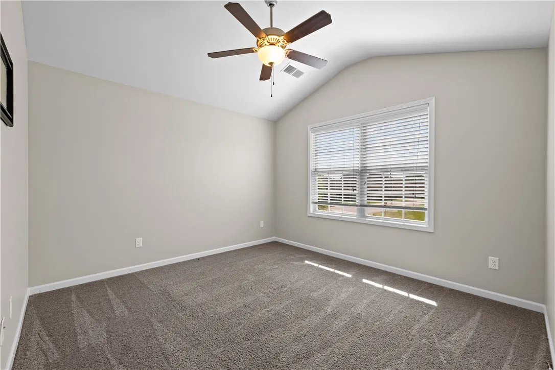 A well-proportioned bedroom offers vaulted ceilings and soft carpeting underfoot.