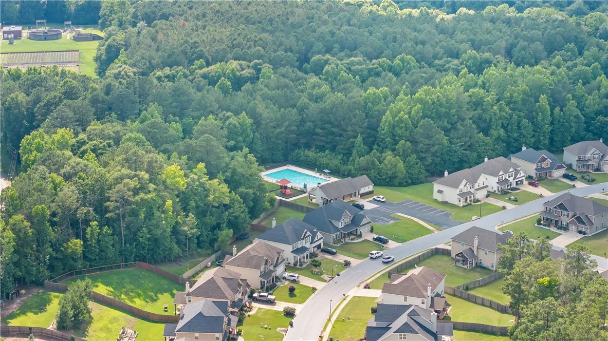 An aerial perspective reveals a serene residential community nestled among verdant trees with a refreshing pool.