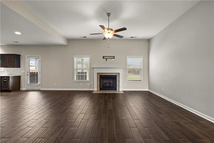 A spacious living area with warm wood flooring centers around a cozy fireplace, perfect for gatherings.