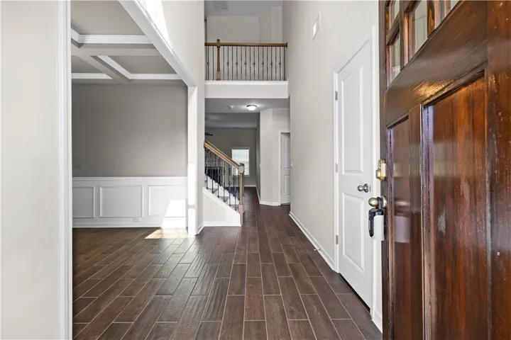 Step into a luminous entryway featuring rich wood flooring and a grand staircase.