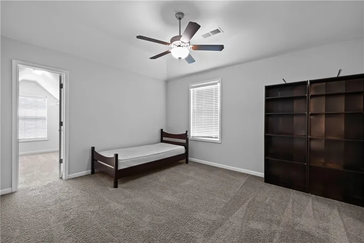 A comfortable bedroom with soft carpeting and a ceiling fan for year-round comfort.