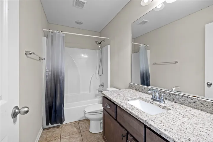 A pristine bathroom featuring a vanity with granite counters and a clean shower/tub combination.