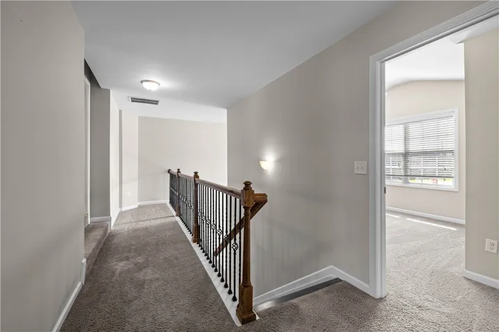 Upper-level landing connecting private spaces with comfortable, neutral carpeting and classic balustrade.