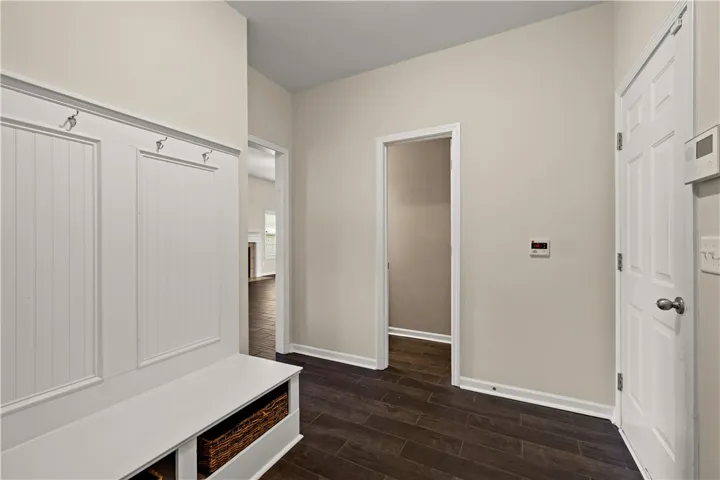 A welcoming entryway with dark wood flooring, a built-in bench, and coat hooks awaits.