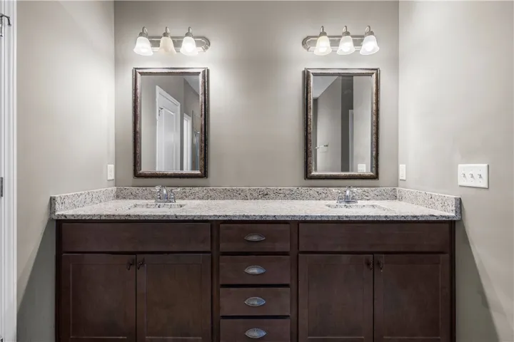 Twin vanities with granite counters and rich cabinetry create a balanced and functional primary bath.