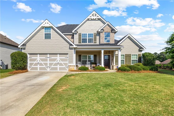 A welcoming facade with a classic porch, a neatly paved driveway, and meticulously manicured landscaping.