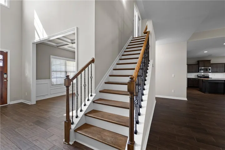 A grand staircase with elegant wrought iron balusters ascends gracefully, complemented by rich wood flooring.
