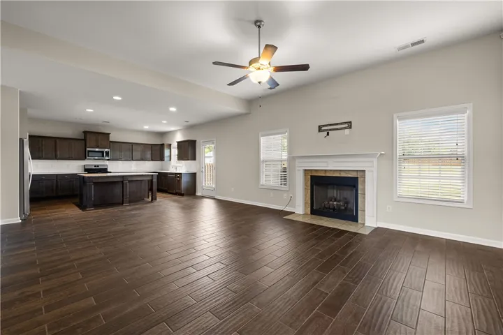 An open-concept living area presents a kitchen island and a cozy fireplace with tile surround.