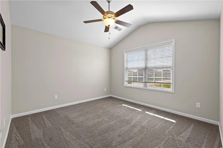 A well-proportioned bedroom offers vaulted ceilings and soft carpeting underfoot.