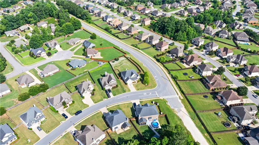 An aerial perspective reveals a well-maintained neighborhood with individual homes nestled among verdant lawns and mature trees.