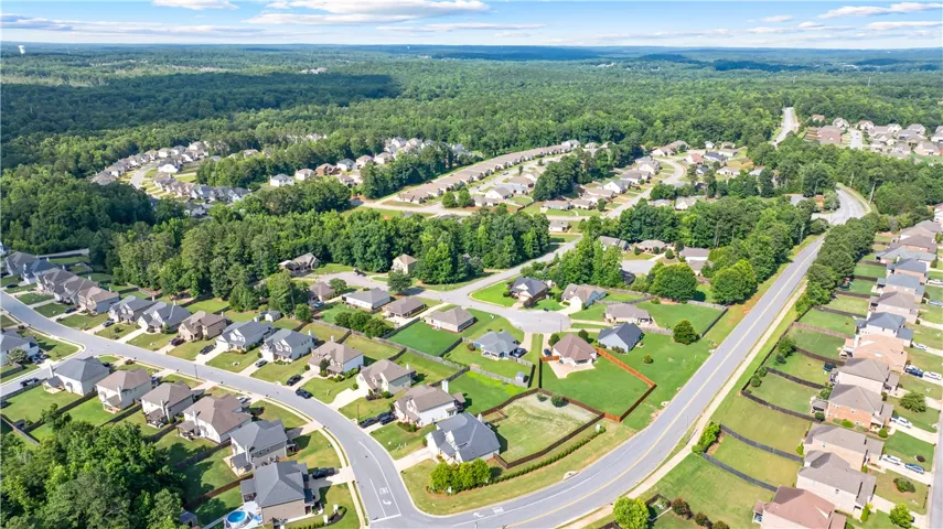 An aerial perspective reveals a vibrant suburban community nestled against a backdrop of dense, verdant woodlands.