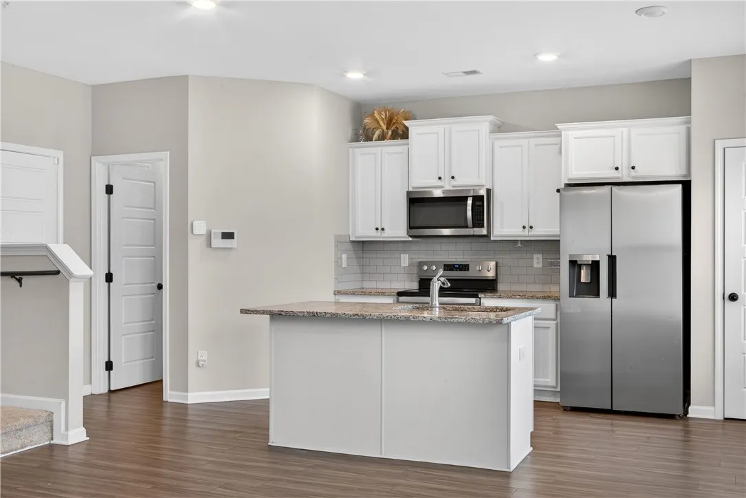 A contemporary kitchen features a functional island with granite counters and sleek stainless steel appliances.