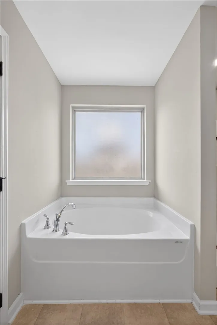 A deep soaking tub awaits relaxation, perfectly positioned beneath a privacy window.