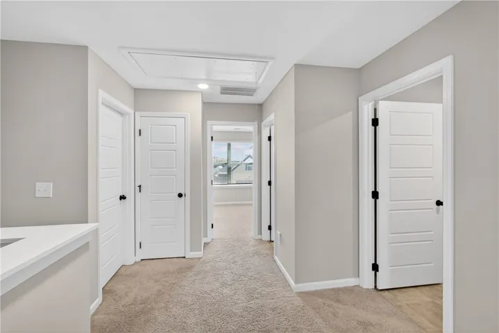A well-lit hallway with carpeted flooring provides a seamless flow throughout the home.