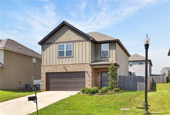 A welcoming facade with a blend of brick and siding, featuring an integrated garage and manicured front landscaping.