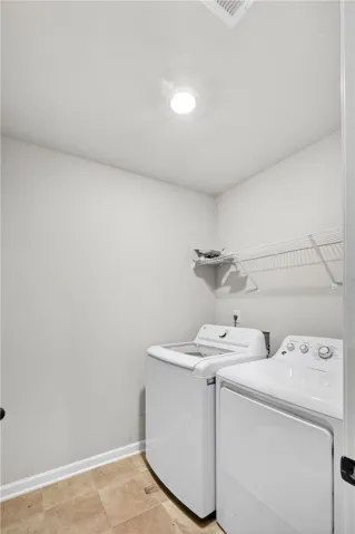A well-organized laundry area offers a top-load washer, a front-load dryer, and convenient wire shelving for storage.