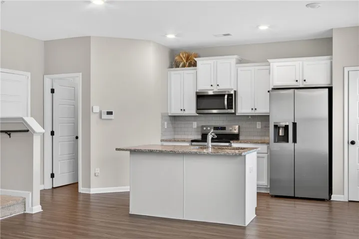 A contemporary kitchen features a functional island with granite counters and sleek stainless steel appliances.