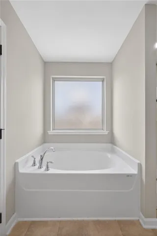 A deep soaking tub awaits relaxation, perfectly positioned beneath a privacy window.