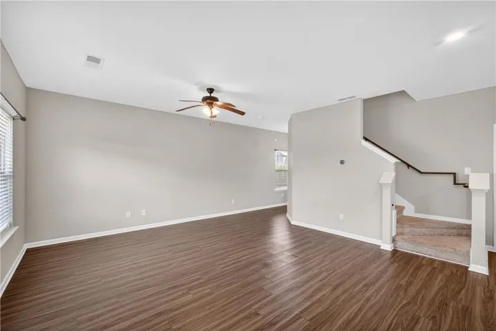 Laminate wood flooring sweeps across this open-concept living area, featuring a staircase with carpeted treads.