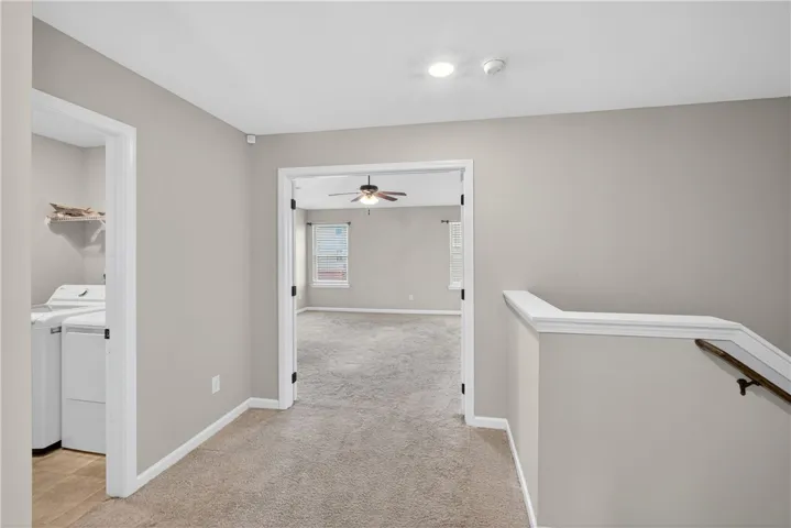 A versatile upper-level landing with plush carpeting, offering easy access to the laundry area and an additional room.