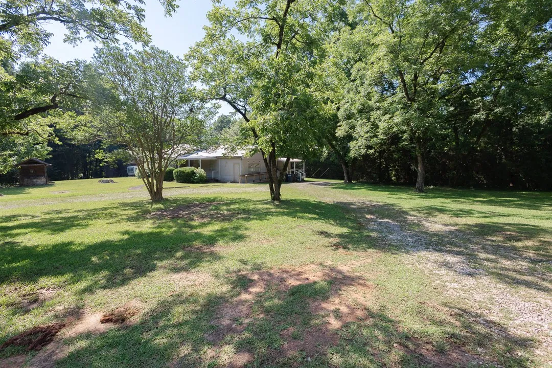 A tranquil estate nestled amidst mature trees, offering ample green space and a welcoming front porch.