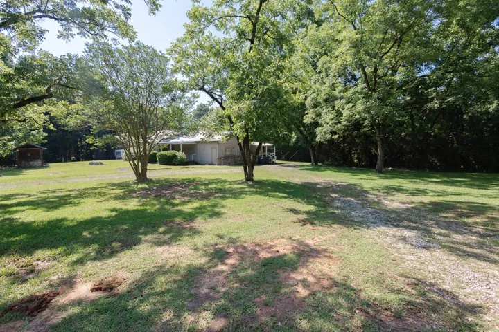A tranquil estate nestled amidst mature trees, offering ample green space and a welcoming front porch.