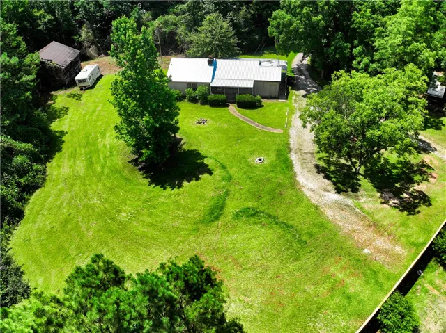 An aerial perspective showcases a home nestled amidst lush, verdant landscapes and mature trees.