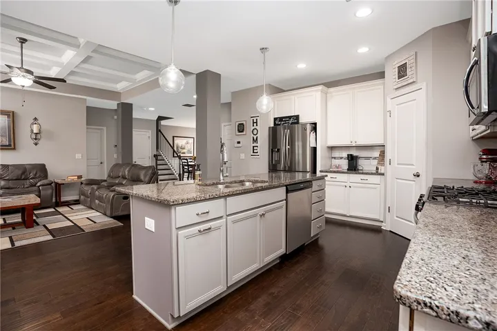 An open-concept living area boasts a modern kitchen island with pendant lighting and rich hardwood flooring.