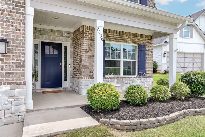 Brick and stone accents adorn this inviting entryway, featuring a navy front door with sidelight windows.