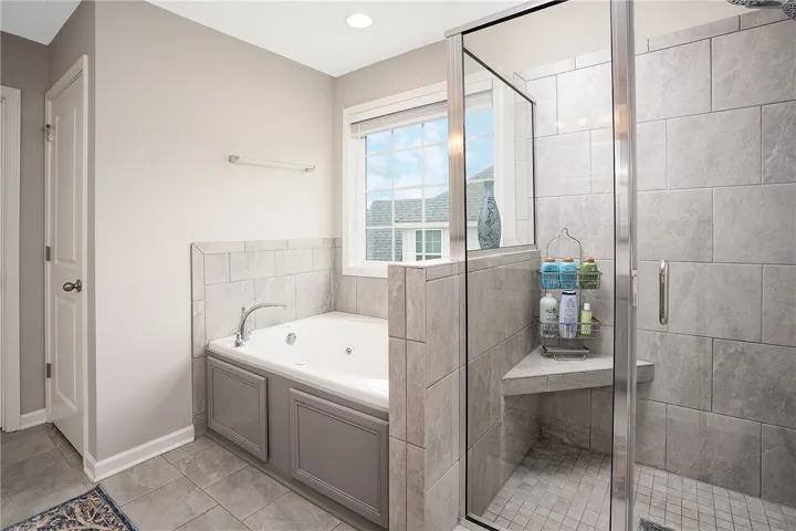 Relax in this luxurious primary bathroom, featuring a deep jetted tub and an adjacent  shower.