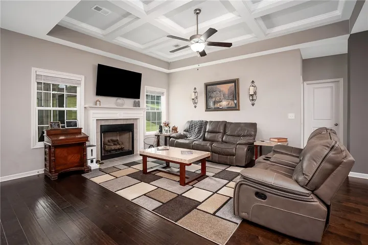 Coffered ceilings crown this inviting living space, complete with rich hardwood floors and a cozy fireplace.