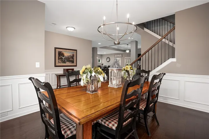 A graceful dining room with wainscoting and dark hardwood floors flows seamlessly into the main living areas.