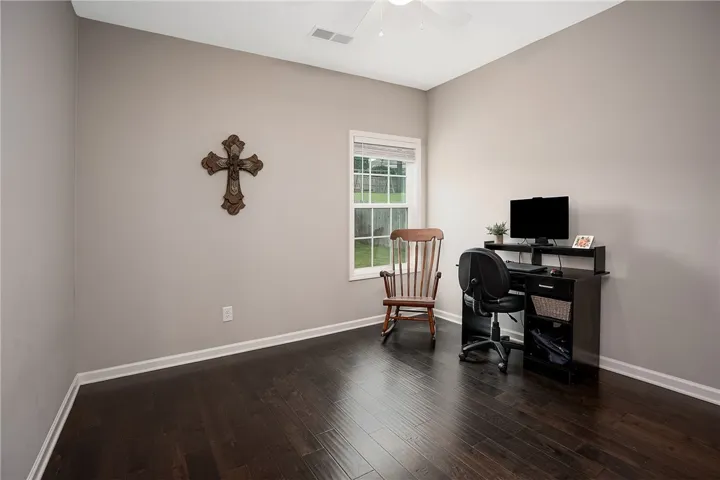 Rich hardwood floors complement neutral walls in this versatile bedroom/office on main level.