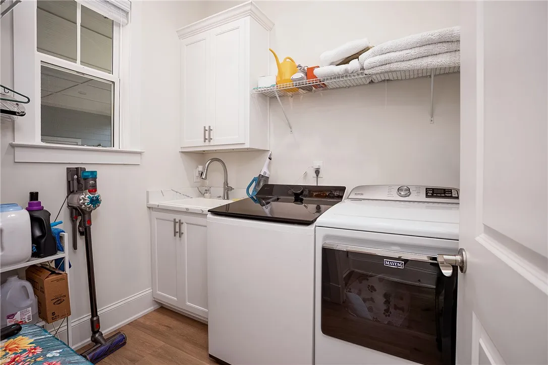 A well-appointed utility room features a sink with elegant cabinetry and practical wood flooring.