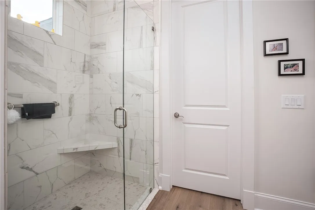 A glass-enclosed shower offers sleek modern design and a built-in bench.