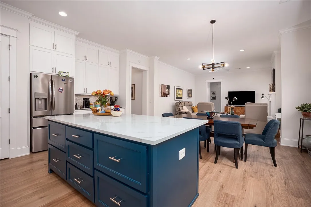 An inviting open concept living space features a spacious island and sleek wood flooring.