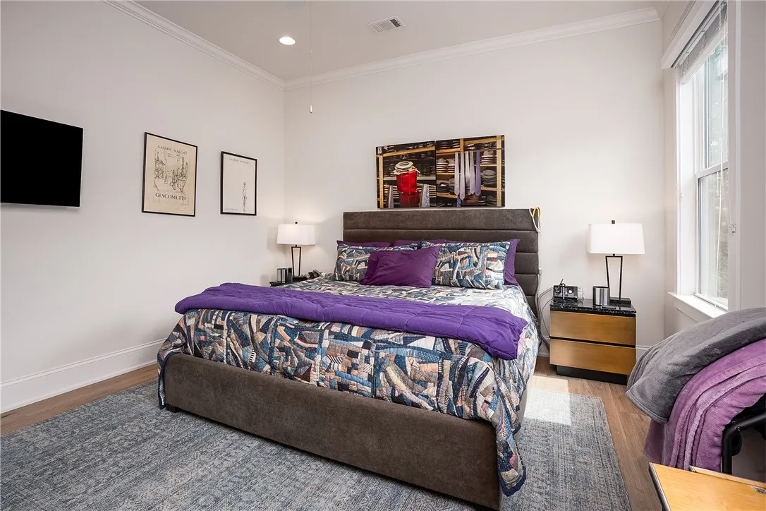 Hardwood floors and tall ceilings define this well-lit bedroom space.