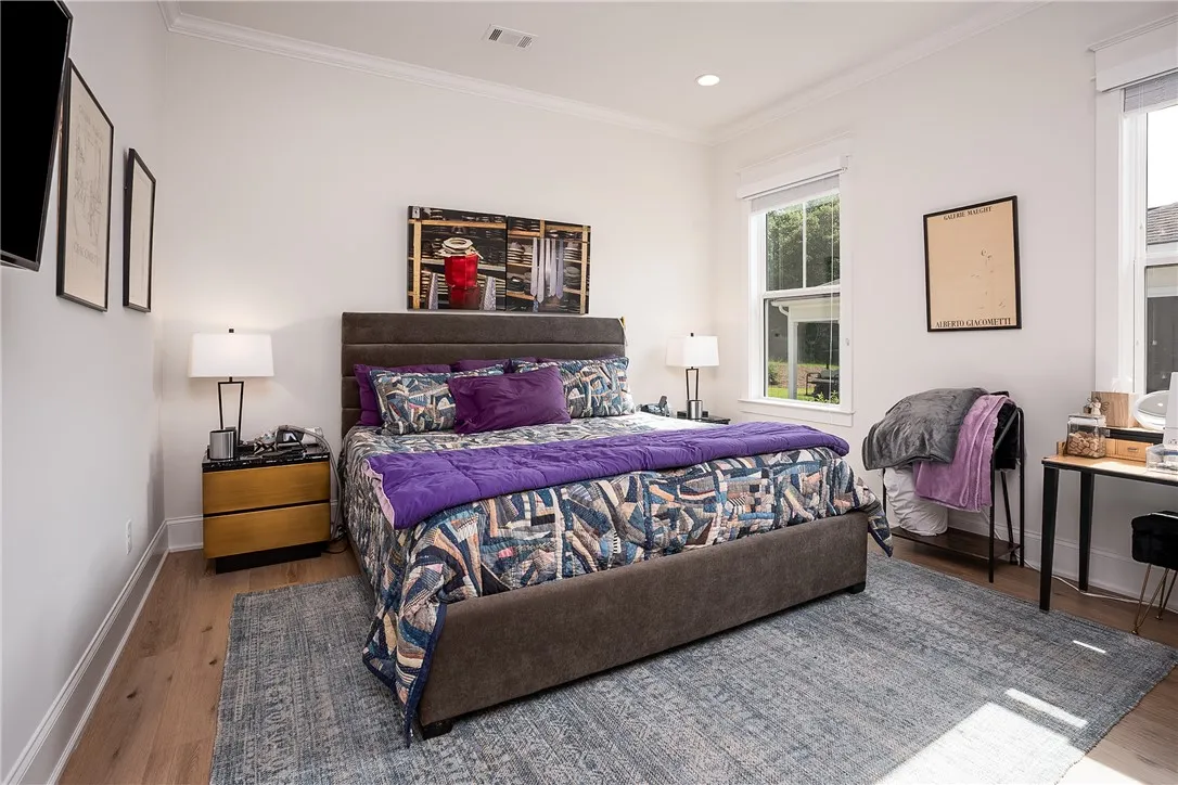 Natural light floods this spacious sleeping area with warm hardwood flooring.