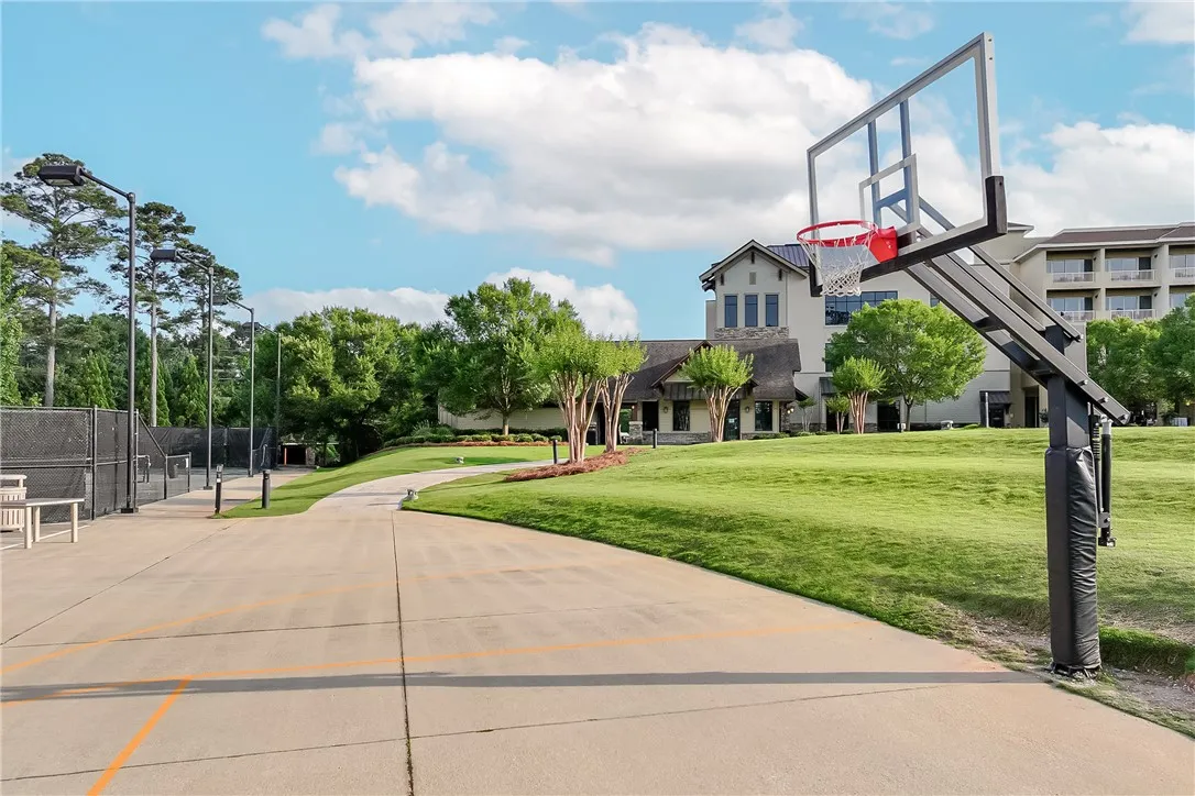 An inviting outdoor sports complex featuring a tennis court and basketball hoop with a large building in the background.
