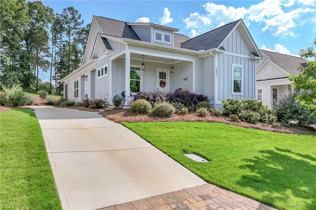 A welcoming front facade with a covered entry, lush landscaping, and a broad driveway beckons.