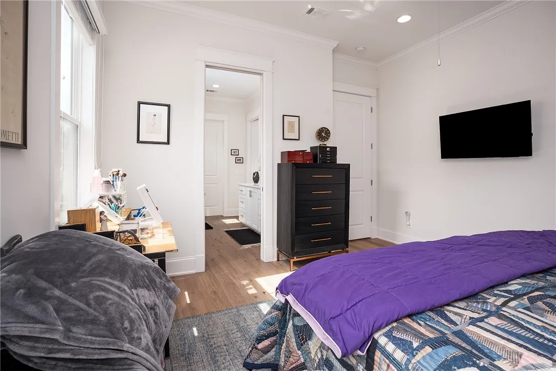 Well-lit sleeping quarters with rich hardwood flooring and convenient en suite bath access.